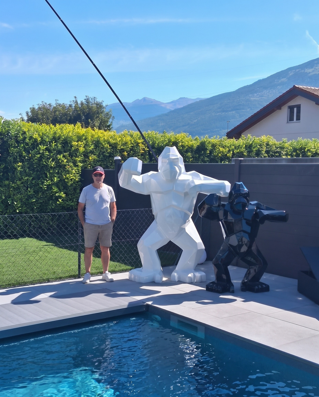 Kongari Collection — sculpture gorille origami Blanc Alpin H200 cm, 2 mètres de haut comparés à un adulte, installée au bord d'une piscine en Valais, Suisse