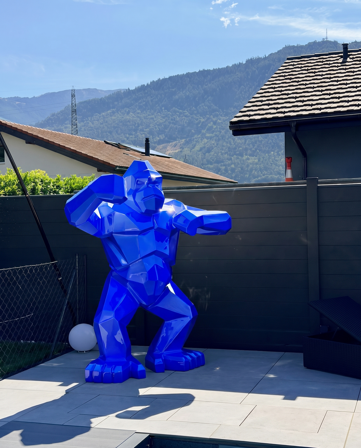 Kongari Collection — sculpture gorille origami Bleu Voltage H200 cm pour intérieur et extérieur, résine laquée anti-UV, installée dans un jardin face aux Alpes suisses