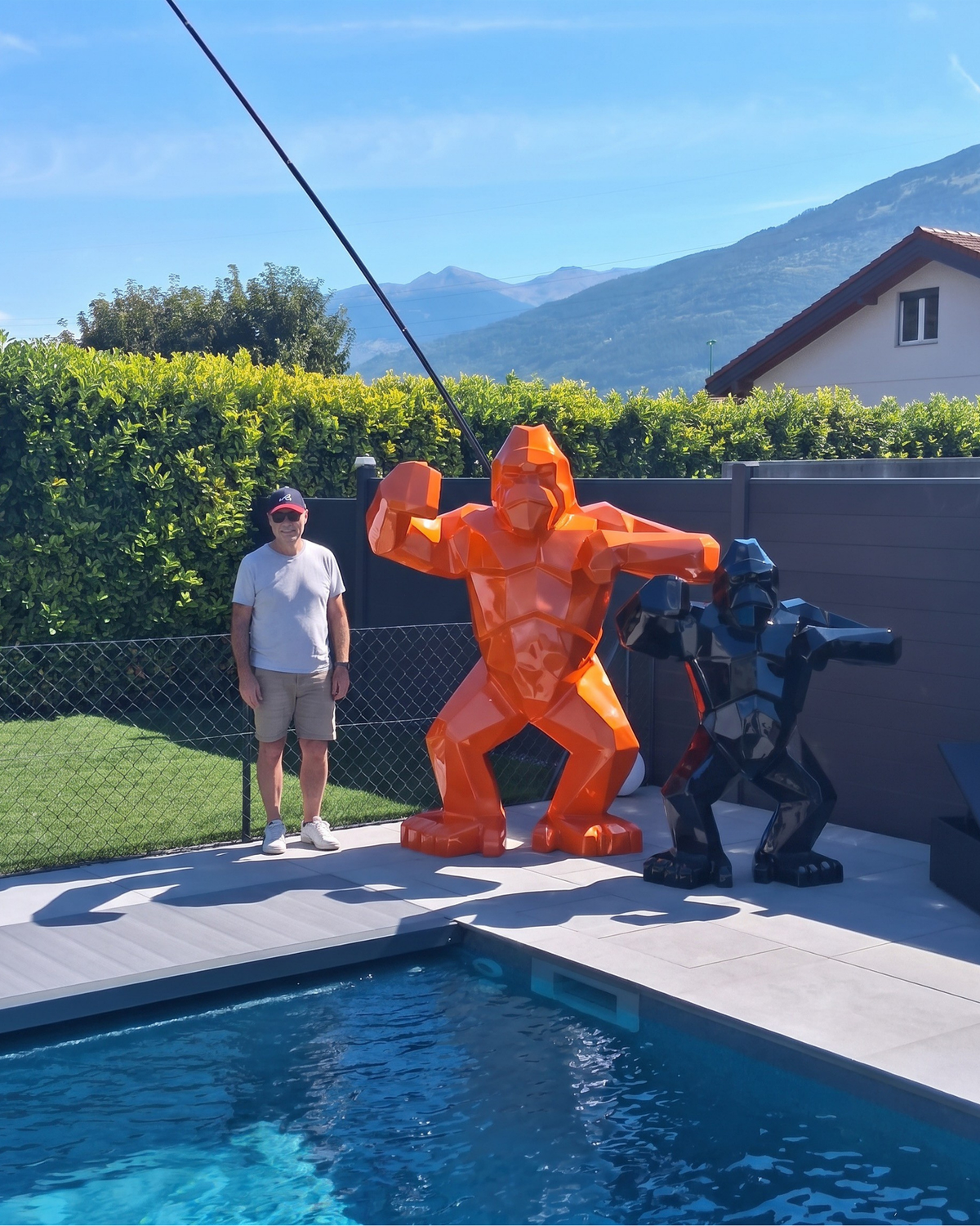 Kongari Collection — sculpture gorille origami Orange Fusion H200 cm, 2 mètres de haut comparés à un adulte, installée au bord d'une piscine en Valais, Suisse